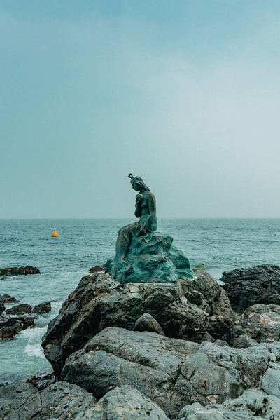 雕像的女人在岩石附近的海洋

